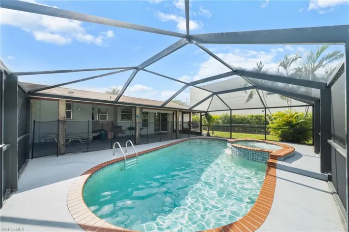 View of pool featuring a sunroom, a patio area, a pool with connected hot tub, and glass enclosure