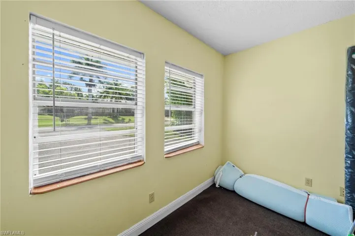 Carpeted spare room with a textured ceiling and baseboards