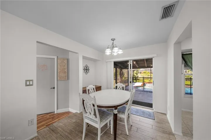 Dining space featuring wood finished floors, a chandelier, and a sunroom