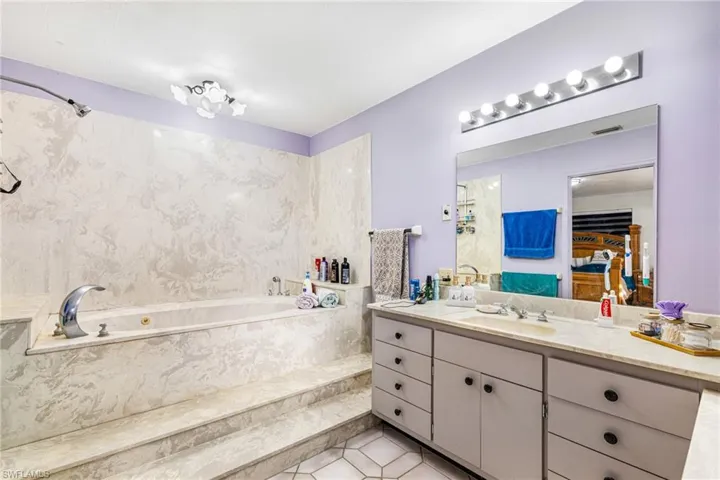 Bathroom with vanity, a garden tub, and light tile patterned floors