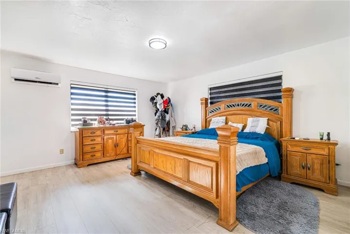 Bedroom with light wood-type flooring and a wall unit AC