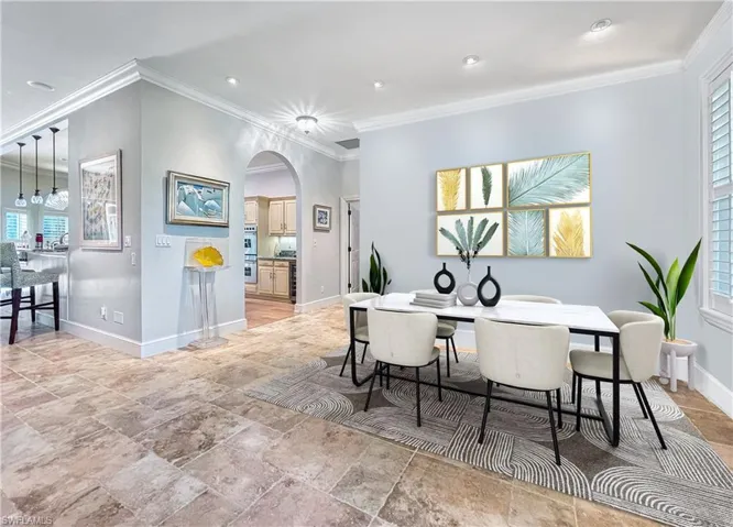 Dining space featuring ornamental molding, arched walkways, baseboards, and recessed lighting