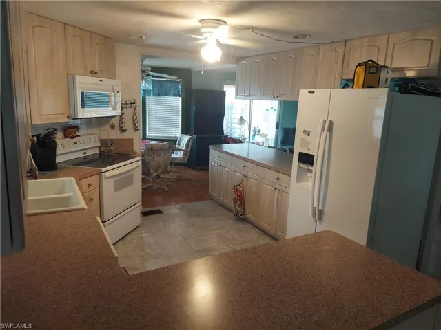 Kitchen featuring white appliances, light hardwood / wood-style floors, sink, light brown cabinets, and ceiling fan
