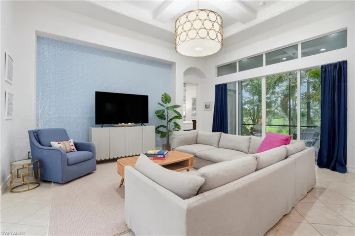 Living area featuring light tile patterned floors, arched walkways, coffered ceiling, beamed ceiling, and a towering ceiling
