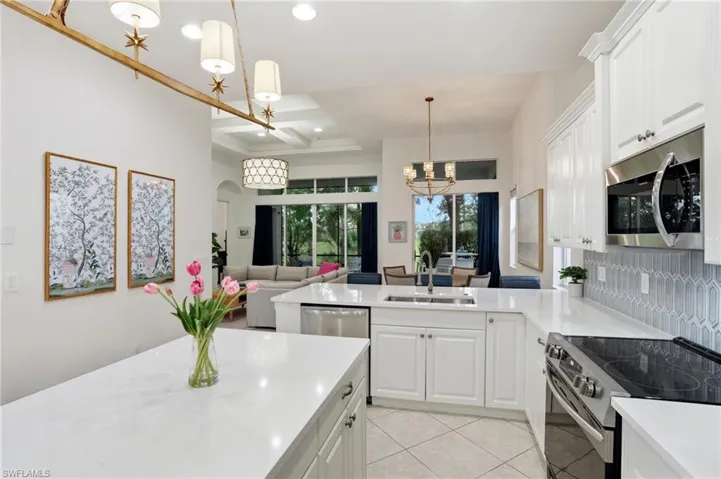 Kitchen featuring appliances with stainless steel finishes, white cabinetry, a peninsula, light tile patterned floors, and decorative light fixtures