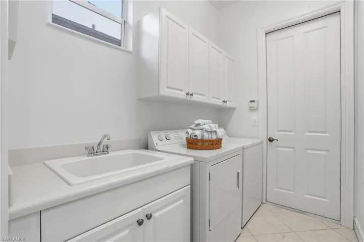 Laundry room featuring light tile patterned flooring, cabinet space, and washer and clothes dryer