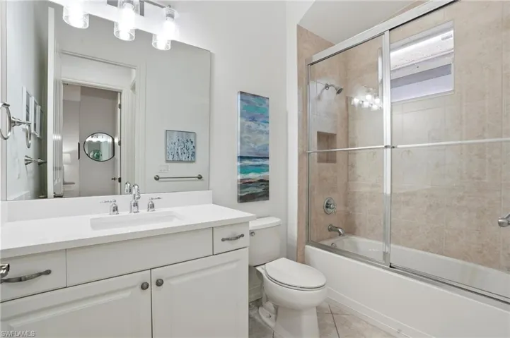 Full bathroom with shower / bath combination with glass door, vanity, and light tile patterned floors