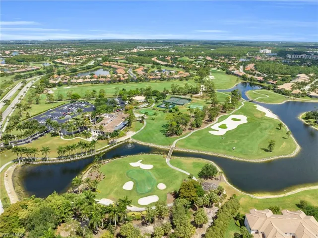 Aerial view of property and surrounding area featuring a golf course and nearby suburban area