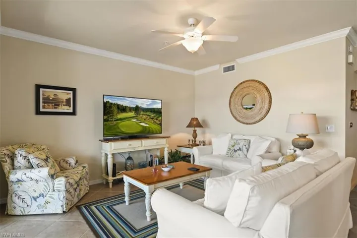 Tiled living area with crown molding and ceiling fan