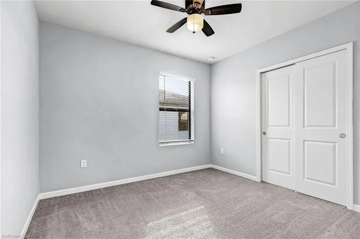 Guest bedroom featuring light colored carpet, a closet, and a ceiling fan