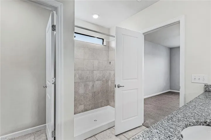 Full bath featuring vanity, a stall shower, and light tile patterned floors