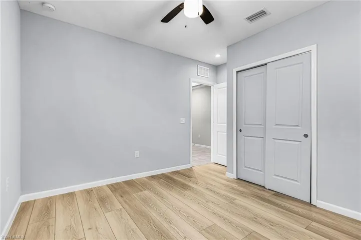 Guest bedroom with luxury vinyl floor, a closet, a ceiling fan, and recessed lighting