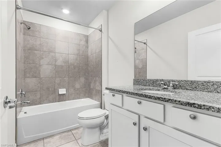 Full bathroom with large granite counter top vanity,  tub/shower combination, and light tile patterned floors
