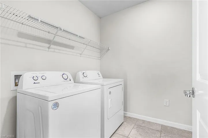 Laundry area with independent washer and dryer and light tile patterned floors