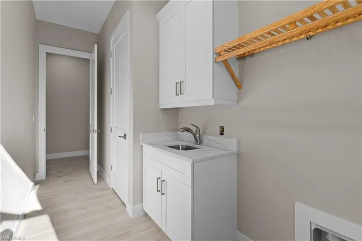 Washroom with sink, cabinets, light hardwood / wood-style flooring, and washer hookup