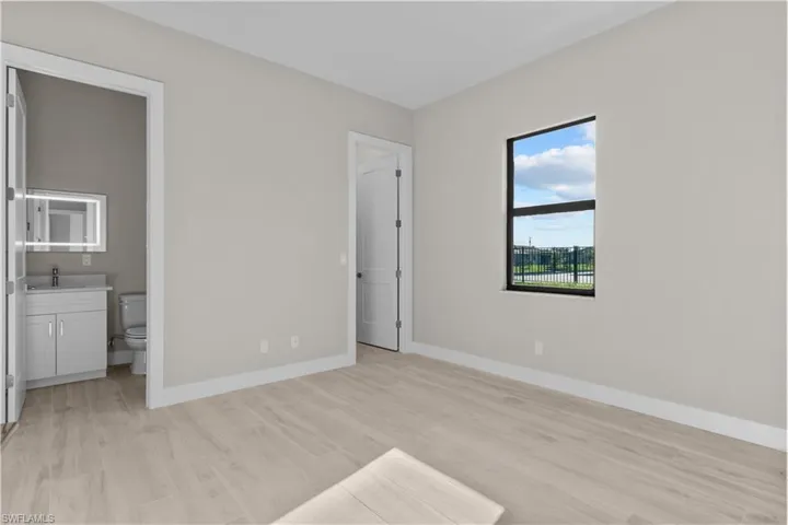 Unfurnished bedroom featuring connected bathroom, sink, and light wood-type flooring