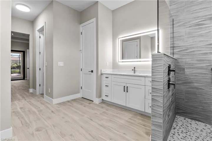 Bathroom with tiled shower, vanity, and hardwood / wood-style floors