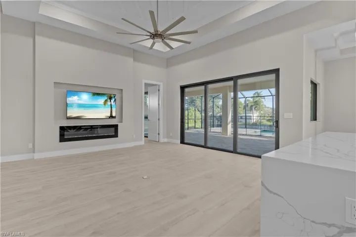 Living room with light hardwood / wood-style floors, a raised ceiling, a towering ceiling, and ceiling fan