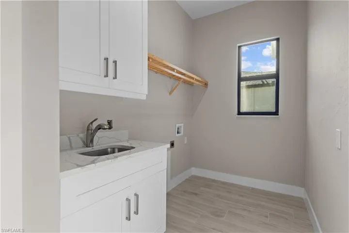 Laundry area featuring sink, cabinets, and washer hookup