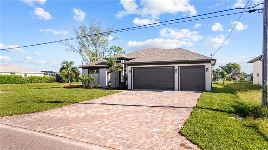 View of front facade featuring a garage and a front lawn