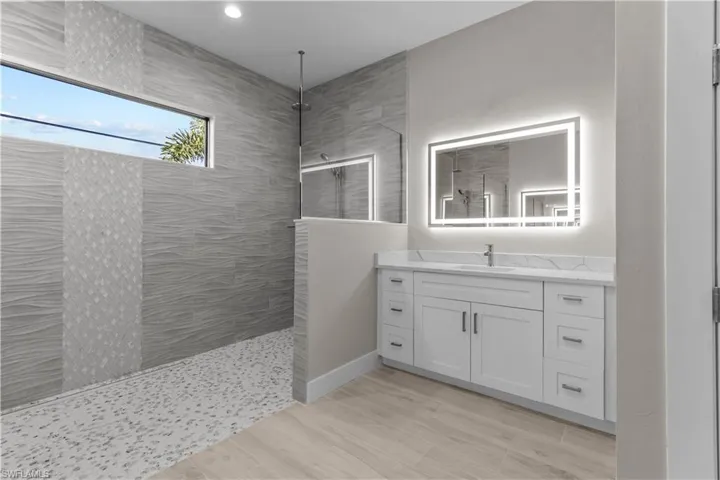 Bathroom with vanity, a tile shower, and tile patterned flooring