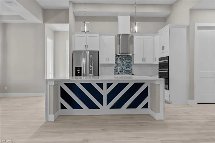 Kitchen with light hardwood / wood-style flooring, decorative backsplash, stainless steel fridge with ice dispenser, white cabinetry, and double oven