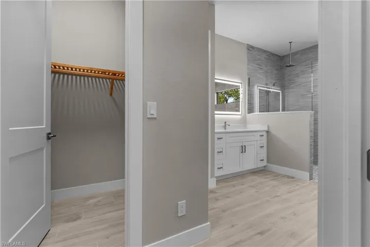 Bathroom featuring tiled shower, hardwood / wood-style floors, and vanity