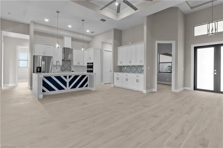 Kitchen with ceiling fan with notable chandelier, stainless steel fridge with ice dispenser, a towering ceiling, light hardwood / wood-style floors, and backsplash