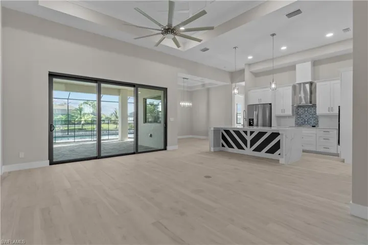 Unfurnished living room with light hardwood / wood-style flooring, ceiling fan, and a raised ceiling