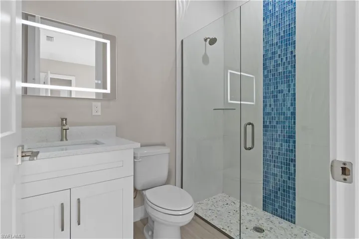 Bathroom featuring walk in shower, toilet, and vanity