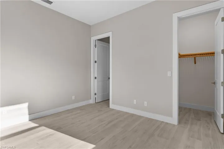 Unfurnished bedroom with light hardwood / wood-style floors, a spacious closet, and a closet