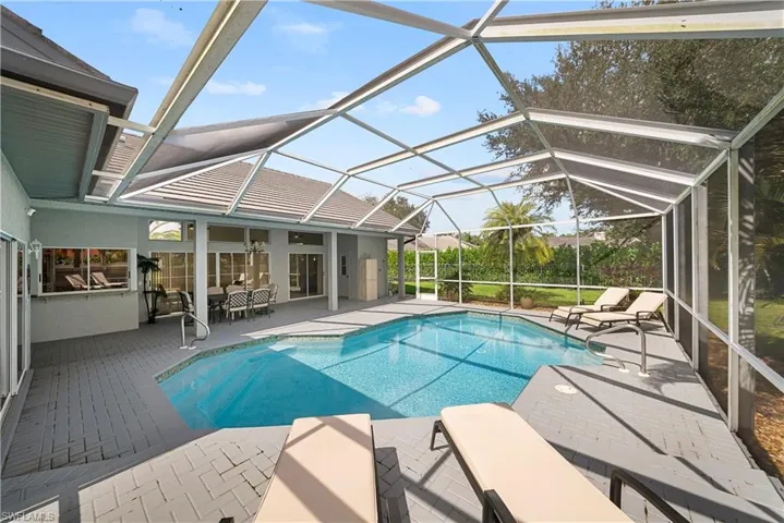 Screened lanai featuring a swimming pool, concrete paver decking, and an integrated pass-through window to the interior