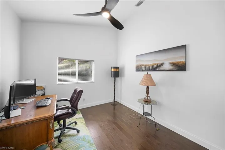 High-ceiling room with wood-finish flooring, matte black three-blade ceiling fan, and window featuring horizontal blinds