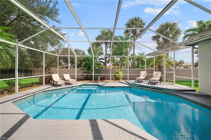 Screen-enclosed swimming pool featuring a decorative tile border, a stepped entry, and a paver patio area