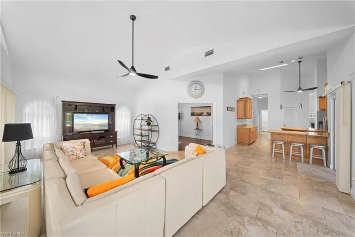 Vaulted ceilings featuring recessed lighting, tile flooring throughout, built-in cabinetry, and a breakfast bar with pendant lighting