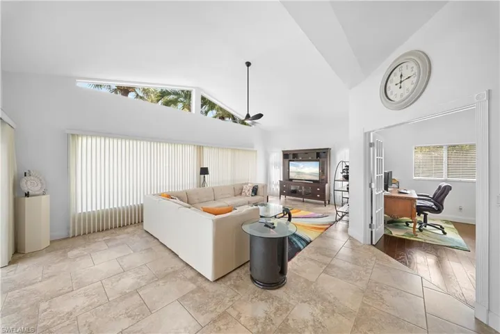 Vaulted ceilings featuring clerestory windows, large-format tile flooring, and French doors