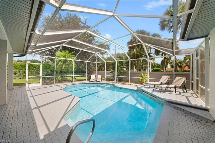 Screened-in outdoor enclosure featuring a private swimming pool, herringbone-patterned paver decking, and metal pool railing