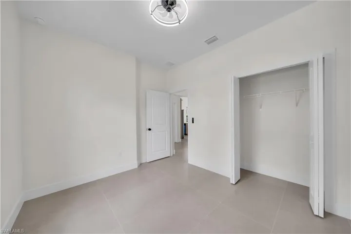 Recessed lighting, light tile flooring, white walls, white trim, and a bi-fold closet door