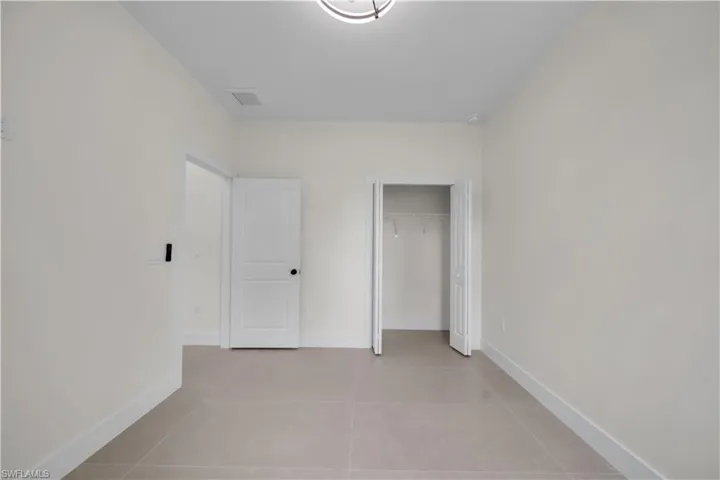 Recessed lighting, light-toned walls, tile flooring, and white interior doors