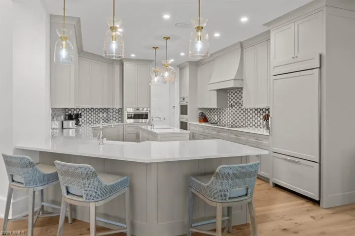 Kitchen featuring a peninsula, a breakfast bar area, light stone countertops, hanging light fixtures, and recessed lighting