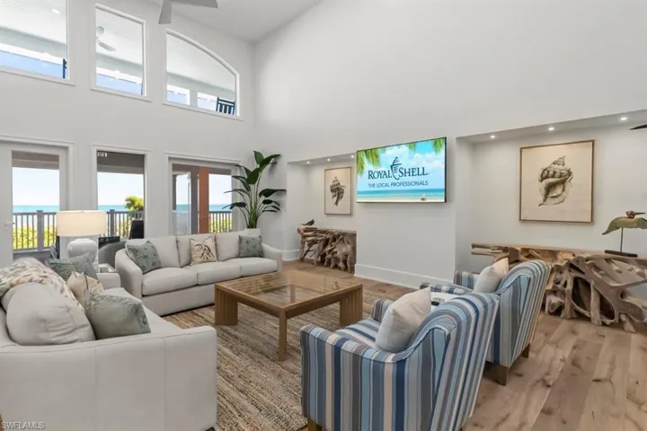 Living area with wood finished floors, a towering ceiling, and recessed lighting