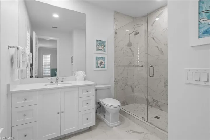 Bathroom with a marble finish shower, vanity, and light marble finish floors