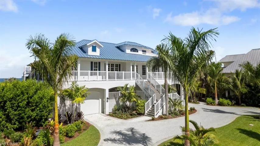Coastal inspired home featuring gravel driveway, a metal roof, stairs, an attached garage, and stucco siding