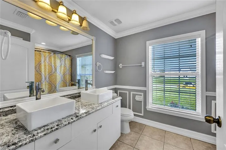 Main Bathroom featuring tile flooring, crown molding, new granite tops, sinks & faucets