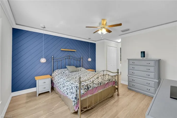 Main Bedroom with light hardwood wood-style updated laminate flooring, ceiling fan, crown molding, & two walk in closets