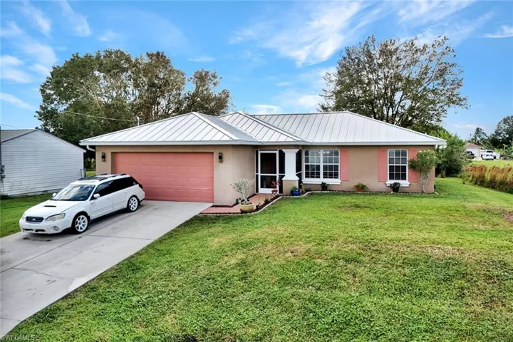 Ranch-style home featuring a garage and a front lawn