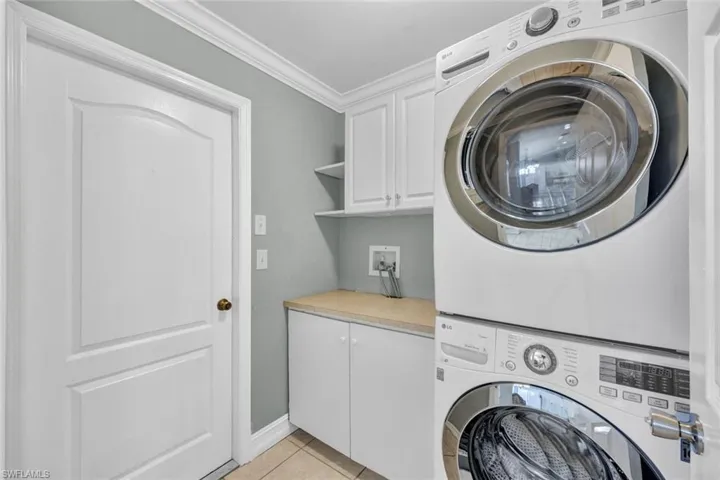 Inside laundry area with crown moldings with upper & lower cabinets for storage