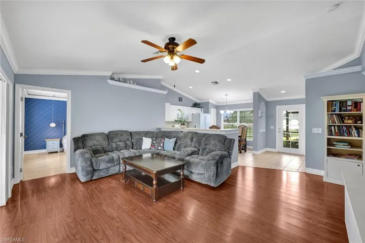 Living room with light wood-laminate flooring, vaulted ceiling, and ceiling fan