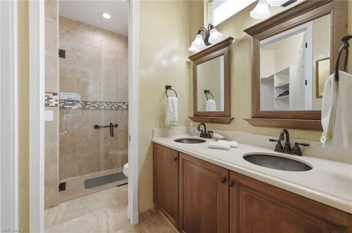 Full bath with double vanity, a shower stall, and recessed lighting