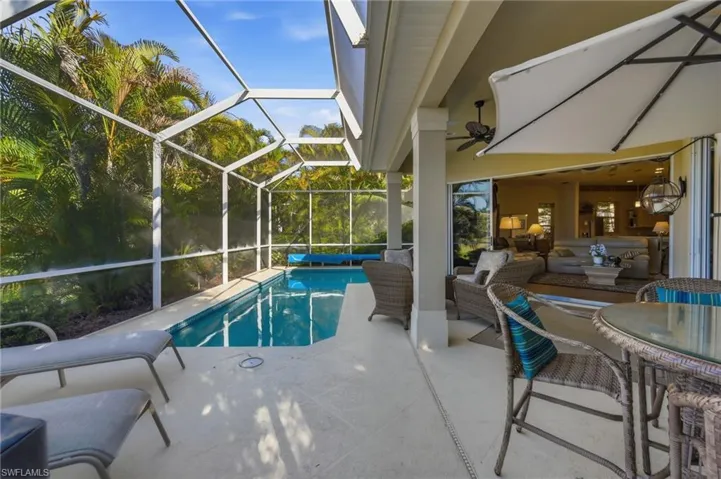 Outdoor pool featuring a patio area, glass enclosure, a sunroom, and an outdoor living / dining area